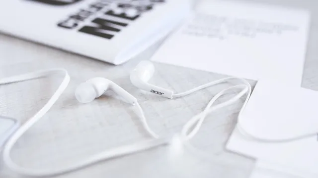 Earbuds and a notebook on a white desk