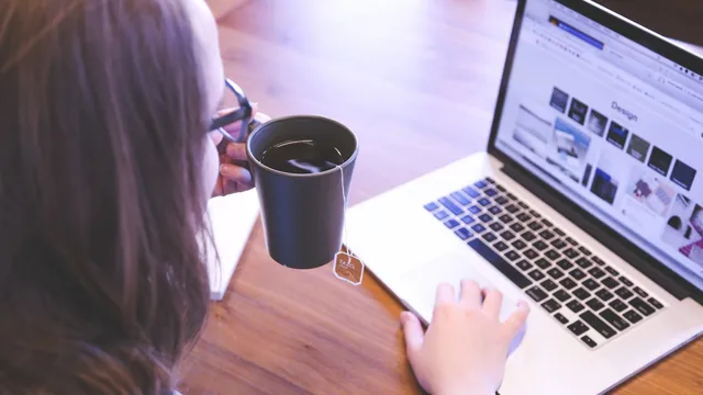 Person working on a laptop with a cup of coffee